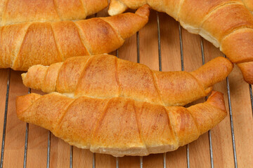 A close-up shot of freshly baked golden croissants cooling on a wire rack on a wooden table