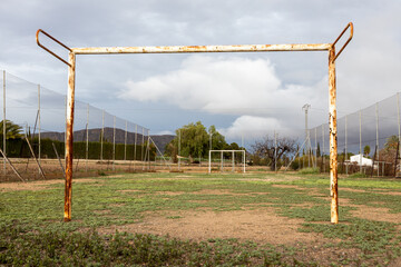 Old abandoned soccer field with rusty goalposts.
