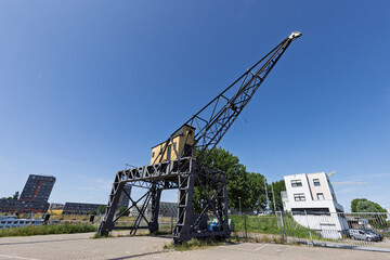 An old, large harbor crane stands idle in a harbor area of Nijmegen, a reminder of the city's industrial past.