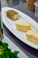 An Array of Flavorful Butters Displayed on a White Platter, Featuring Varieties with Seasonings for Culinary Delight