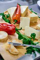 A Rustic Platter of Artisanal Cheeses Surrounded by Fresh Herbs and Colorful Peppers, Perfect for Gourmet Dishes and Charcuterie Boards