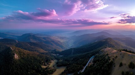 Obraz premium Aerial landscape with mountain peaks, alpine forest, winding road through valley, dramatic sunset, captivating view for adventure or travel stock photo