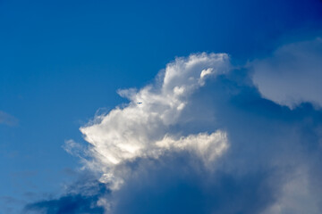 Vibrant Blue sky with a Jet airplane flying against large storm clouds