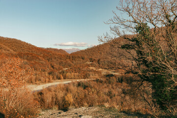 A colorful landscape with high mountains, a beautiful winding river, an autumn forest, and a blue sky with clouds. Autumn in the mountains. Stunning view of the river among the colorful autumn forests