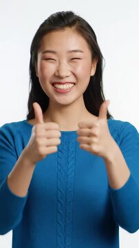A vibrant medium close-up video of a diverse person with a radiant, genuine broad smile & sparkling eyes, enthusiastically giving two thumbs up against a clean, soft bokeh background with text space.
