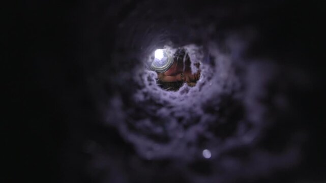 Man inspecting a dryer vent with a flashlight, checking for lint buildup and blockages. The image captures a real-life home maintenance moment, emphasizing fire prevention, appliance safety, and respo