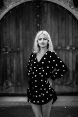 Naklejka premium Portrait of a beautiful blonde girl in a white polka dot dress outdoors. Black and white photo.