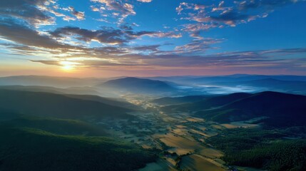 High-altitude aerial of mountain valley at sunset, golden light washing over rolling hills, tranquil and inspiring landscape for meditation or lifestyle stock photo