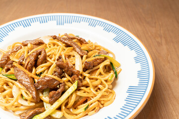 Enjoying asian cuisine with savory noodles, tender beef, and fresh vegetables, served on a stylish plate
