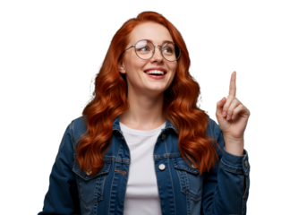 Cheerful young woman with wavy red hair in a denim jacket, smiling and pointing upwards, exuding positivity and inspiration