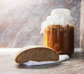 Glass jar with fermented drink. Fermented drink from a scratch. Rye bread on a white linen tea towel on the foreground. 