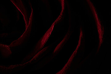 An abstract, close-up view of a dark red rose petals with a velvety or satin texture, with subtle sparkling highlights, creating a pattern of undulating lines.