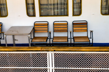 Chairs arranged neatly on a deck of a boat in bright sunlight with a calm ocean view in the...