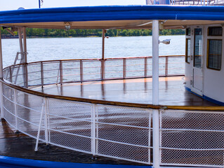 Beautiful view of a deck on a riverboat during a sunny afternoon, surrounded by calm waters and lush greenery in the background