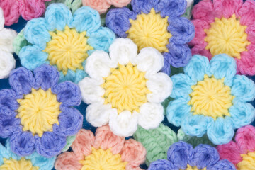 Top view close up of hand crochet spring flowers in pink, purple, ble, peach and white.