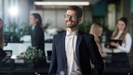 A man in a suit stands in front of a group of people