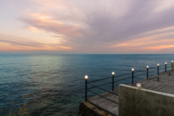 Obraz premium Beautiful sunset over sea with pier and glowing lanterns. Tranquil coastal scene in Croatia. Romantic, peaceful atmosphere, perfect for travel, nature themes.