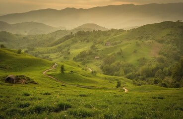 Serene mountain landscape at sunset. Winding dirt road leads eyes towards horizon through rich green fields and scattered trees. Warm orange and yellow hues create peaceful atmosphere.