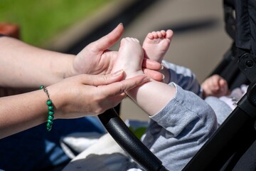 Fototapeta premium Mother's hands massaging baby's feet in stroller, showing loving care and infant wellness through gentle foot therapy