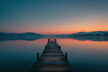 Obraz premium Peaceful sunrise over a still lake with a wooden dock