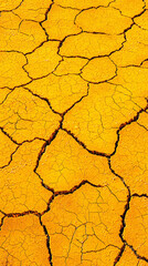 Parched, cracked soil in warm orange and brown tones creates a natural, abstract pattern. Concept of drought, arid land, dry climate, texture, earth.