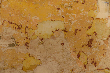 A full frame abstract texture of a weathered and peeling painted wall in shades of yellow, beige, and pink.
