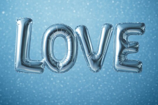 Metallic balloon letters spelling LOVE on sparkling blue background, shiny and creative party decoration for romantic and festive concepts. Ai generative