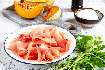 salad ingredients, prosciutto and melon, arugula and basil, mozzarella cheese, balsamic sauce, close-up,
