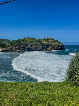 Kasap Beach in Pacitan, Indonesia, showcases pristine white sand, rocky cliffs, and turquoise waters under a clear blue sky