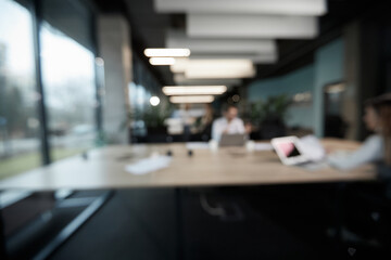 A blurry image of a group of people sitting at a table with laptops