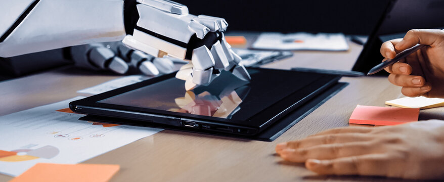 A robotic hand carefully interacts with a tablet on a modern office desk, emphasizing the fusion of technology and creativity in a contemporary workspace.Noogenesis
