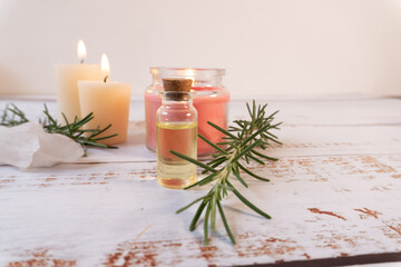 Composition of oils, rosemary branches, quartz, and candles on a wooden table