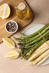 Different raw asparagus spears and spices on wooden table, flat lay