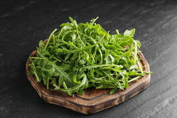 Fresh ripe green arugula leaves on black table, closeup