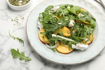 Tasty salad with arugula, cheese, peach, basil and spices on white marble table, above view