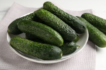 Fresh cucumbers in bowl on white table, closeup