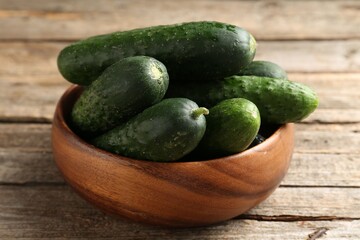 Fresh cucumbers in bowl on wooden table, closeup