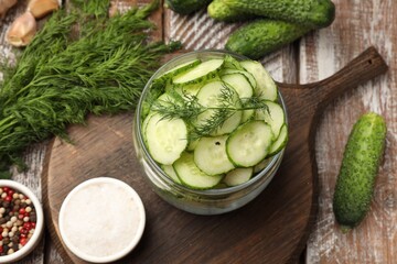 Making pickles. Slices of fresh cucumbers in open jar, spices and dill on color wooden table, flat lay