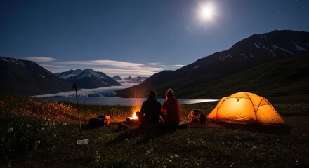 Couple camping at night by a campfire and tent with a moonlit lake and mountains