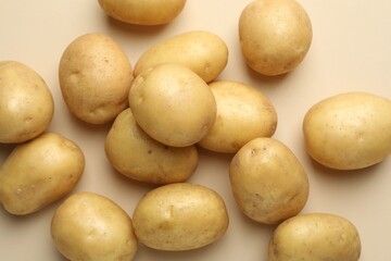 Fresh raw potatoes on beige background, top view