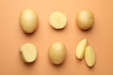Fresh raw potatoes on light brown background, flat lay