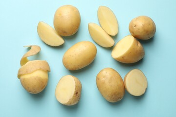 Fresh raw potatoes on light blue background, flat lay