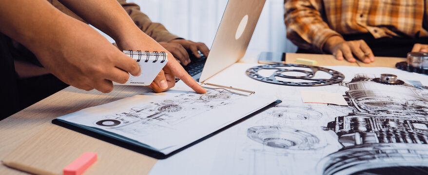 A dynamic scene of a collaborative meeting featuring team members discussing engineering designs with sketches, a laptop, and vibrant sticky notes in a modern office setting. SACTR