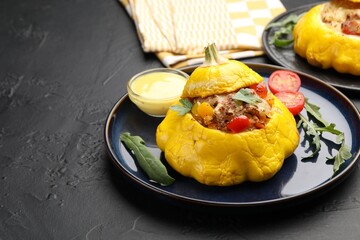Tasty stuffed pattypan squash with sauce on black table, closeup. Space for text