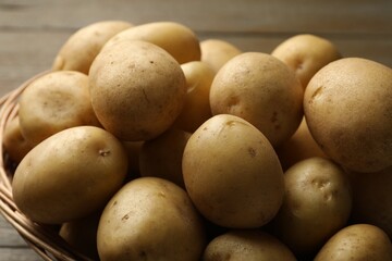 Fresh potatoes in basket on wooden table, closeup