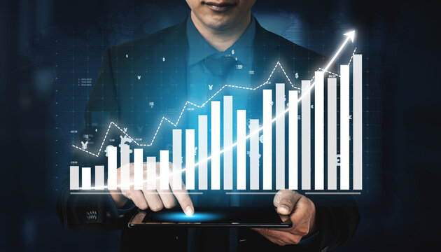 A businessman interacts with a tablet displaying a rising graph, symbolizing data analysis and business growth in a modern office setting. Impute