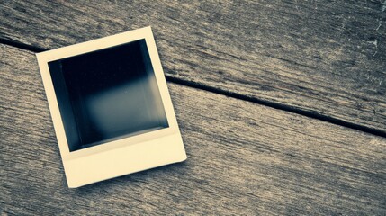 An empty instant camera print rests on a weathered wooden surface, blending modern technology with nostalgic textures,