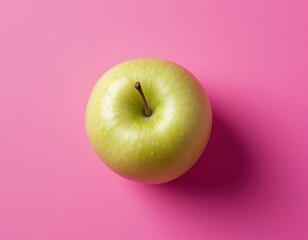 Top view of a green apple centered on a bright pink background, clean and minimal.