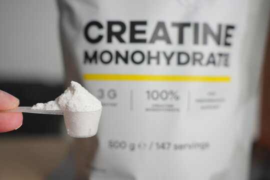 Heaped Scoop of Creatine Powder with Bag in Background