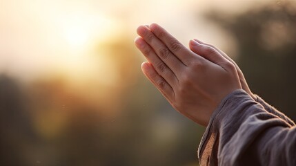 Hands clasped in prayer, sunlight